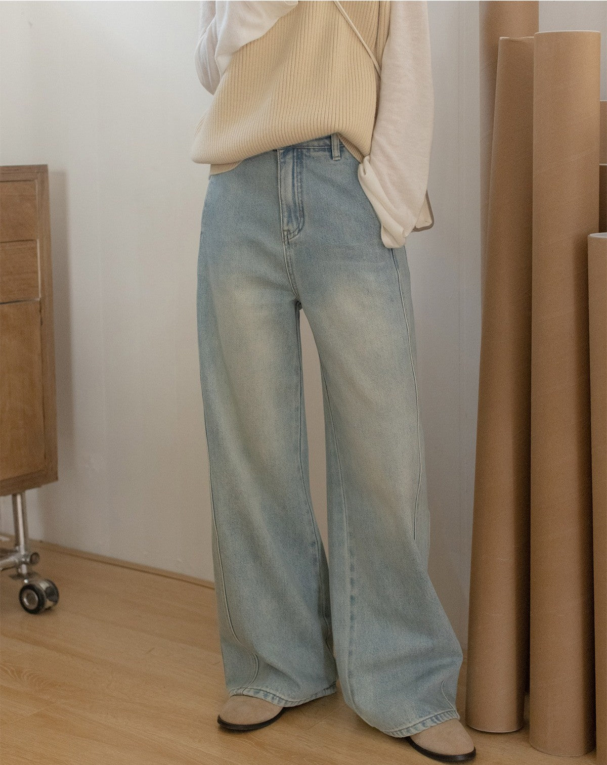 ライトブルーのワイドレッグデニムを着用したモデルが、ベージュのニットと白いトップスを合わせたカジュアルなコーディネート。