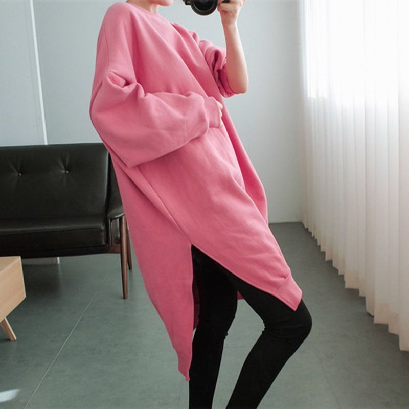 ピンクのオーバーサイズスウェットシャツを着た人が横向きで立っている。