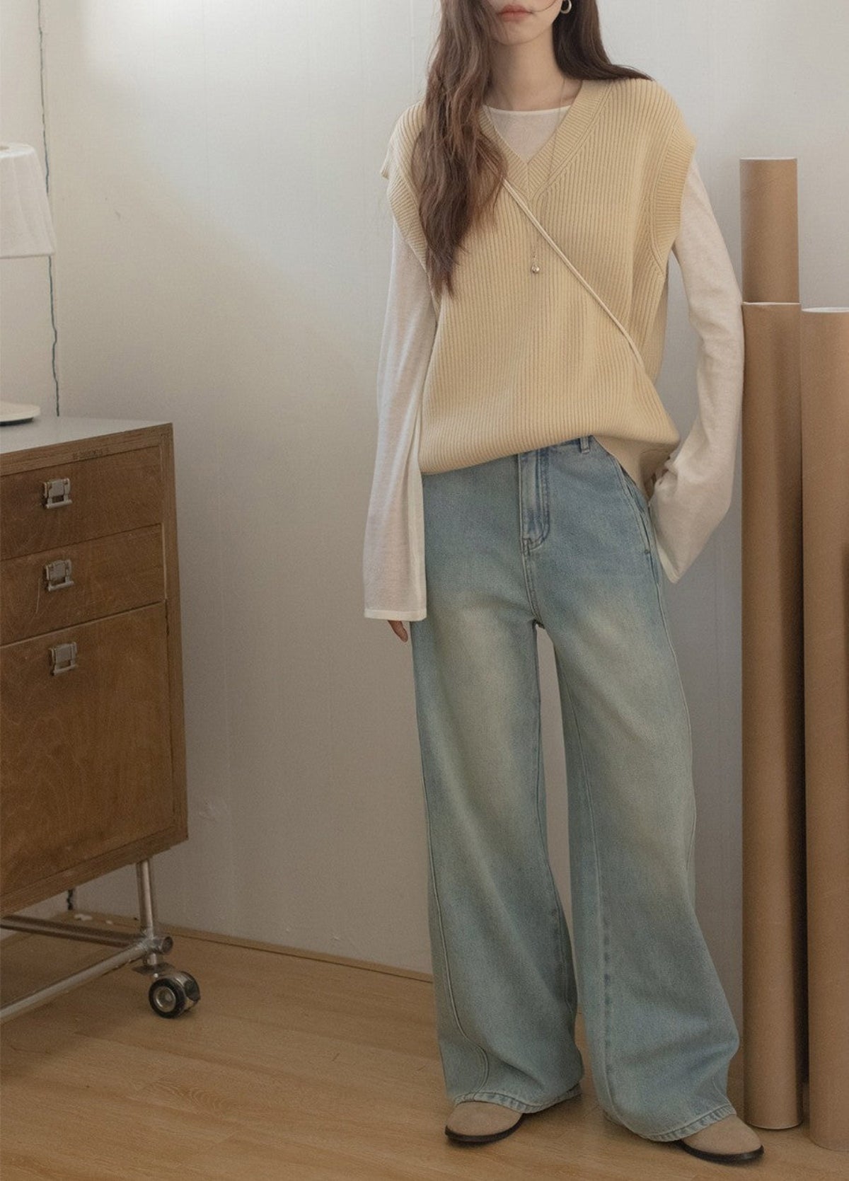 ライトブルーのワイドレッグデニムを着用したモデルが、ベージュのニットと合わせてリラックスした印象のスタイリング。