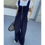 白Tシャツの上にデニムオールインワンを重ね着し、網バッグを持って立っている女性のクローズアップ写真。