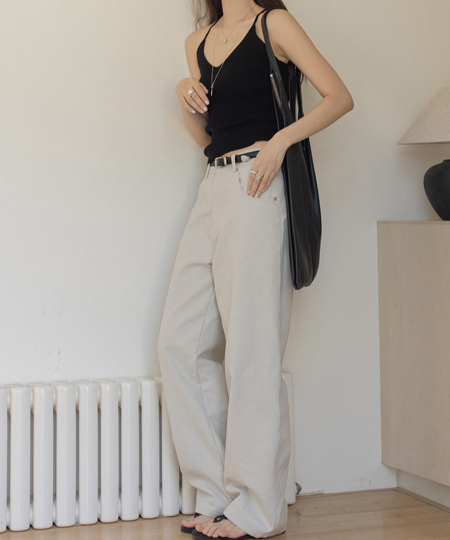 ライトグレーのワイドレッグパンツを履いたモデルが黒いバッグを持ち、黒いタンクトップを着用している。