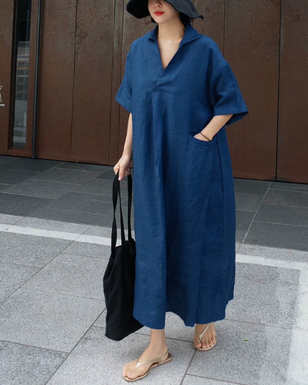 ブルーのリネンドレスワンピースを着用した女性、広がるシルエットと落ち着いた色合いが特徴。