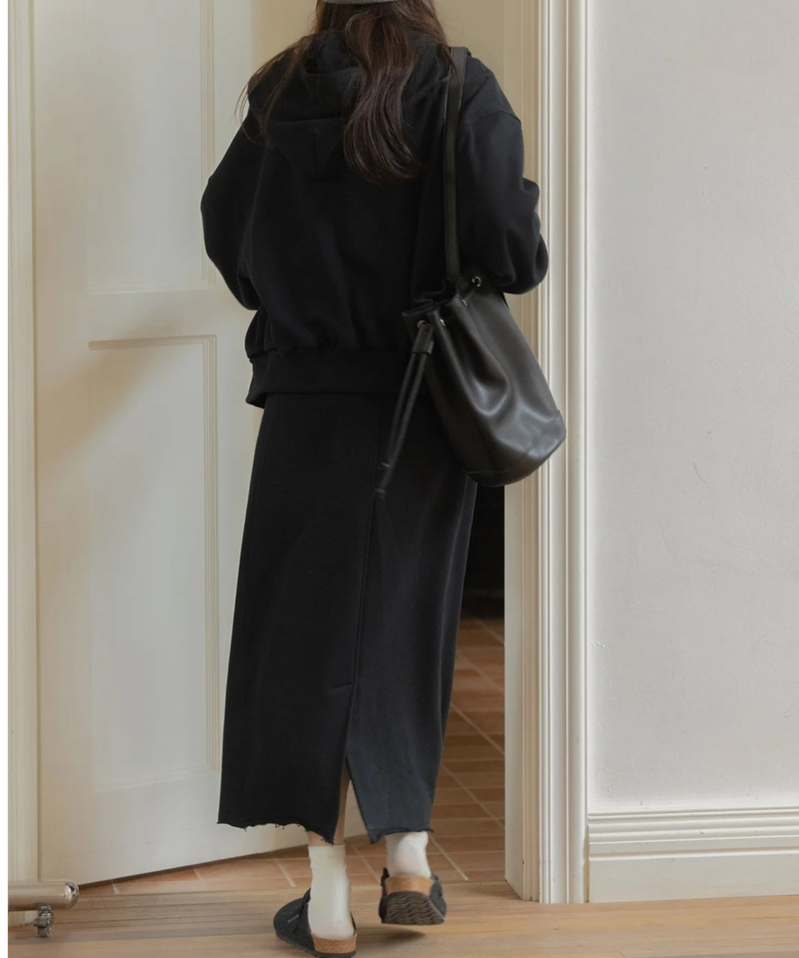 黒のスウェットジップアップパーカーとロングスカートをセットアップで着た女性の後姿。カジュアルな全身
