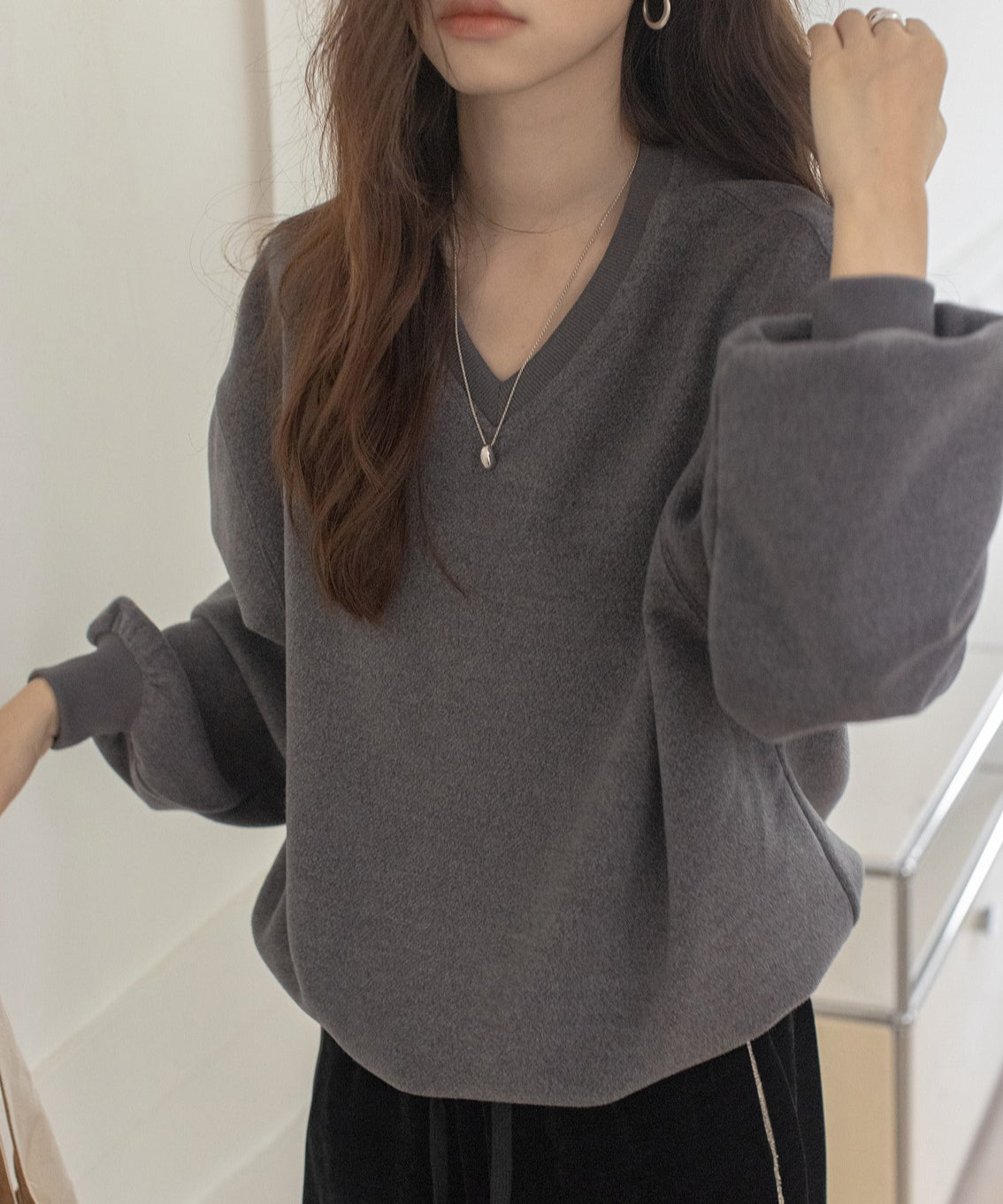 グレーのVネックバルーンスリーブトップスと黒のベロアワイドパンツを合わせた女性のカジュアルな上半身。