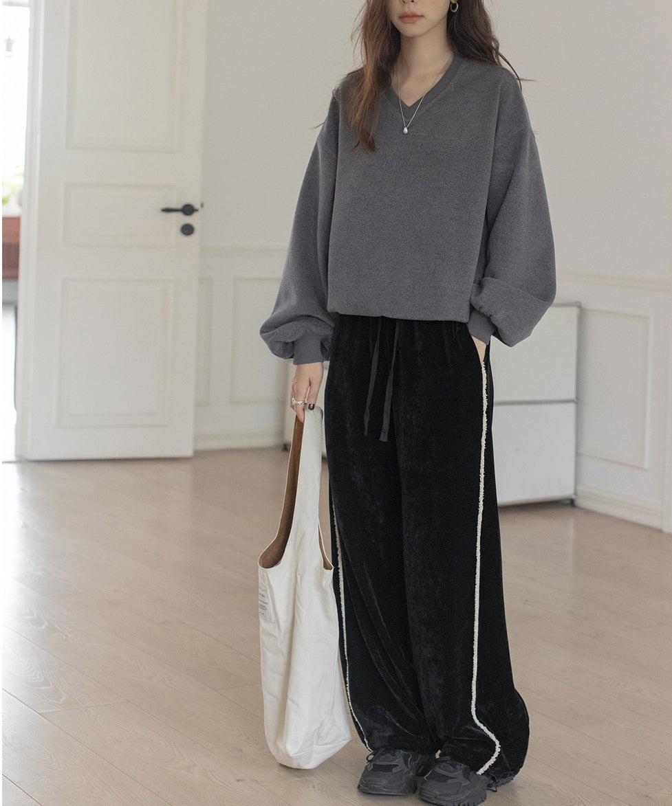 グレーのVネックバルーンスリーブトップスと黒のベロアワイドパンツを合わせた女性のカジュアルな全身。