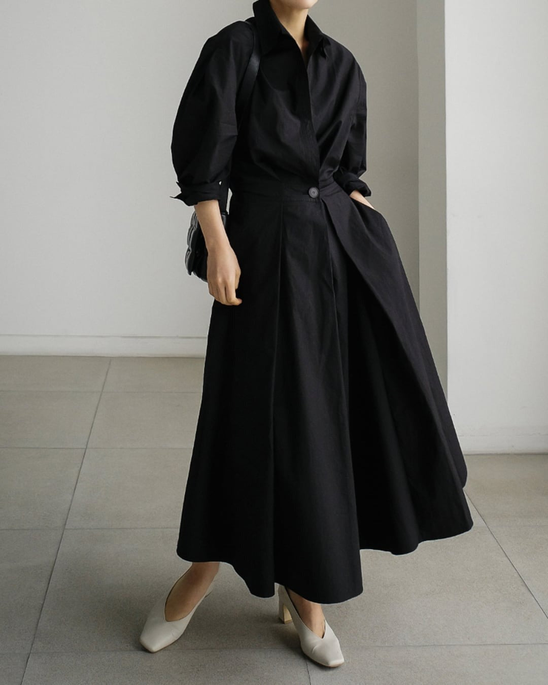ブラックのロングドレスワンピースを着用した女性。シンプルなコーディネートに白いパンプスを合わせた着こなし。