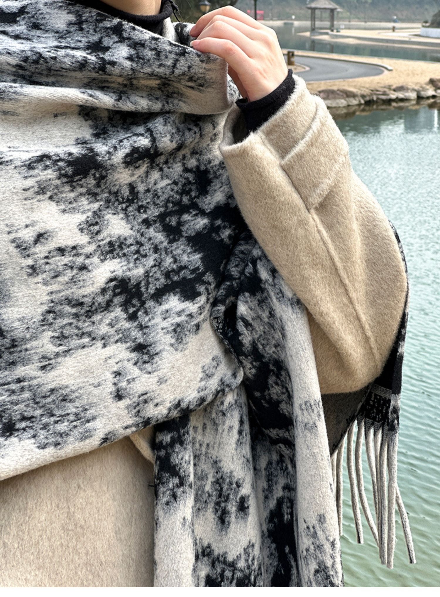 水墨画風の殻のストールを巻いた女性が屋外に立っている写真。