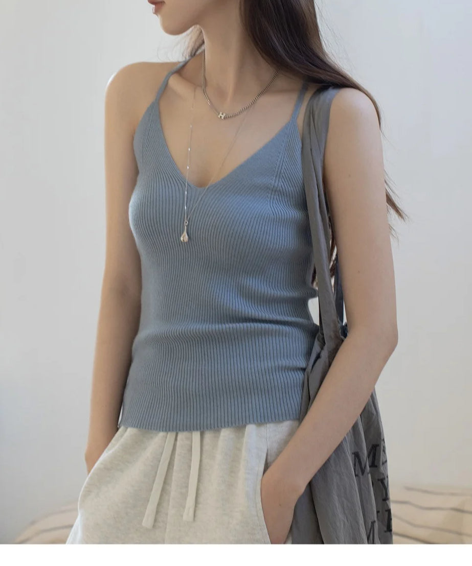 ブルーのリブ編みVネックキャミソールを着用した女性。白のショートパンツやスウェットパンツと合わせ、シルバーのネックレスを着用。