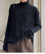 ブラックのリブ編みタートルネックセーターを着用し、茶色のボトムスと合わせた女性の上半身。ゆったりとしたオーバーサイズシルエット。