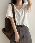 ホワイトのUネックTシャツを着用し、肩から茶色のバッグを下げた女性の上半身。Tシャツをグレーのカーゴポケット付きミニスカートに軽くタックインし、黒いベルトを締めている。