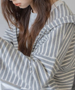 グレーと白の細いボーダー柄のジップアップパーカーを着用した女性の接写ショット。ラグランスリーブの袖の様子が見える