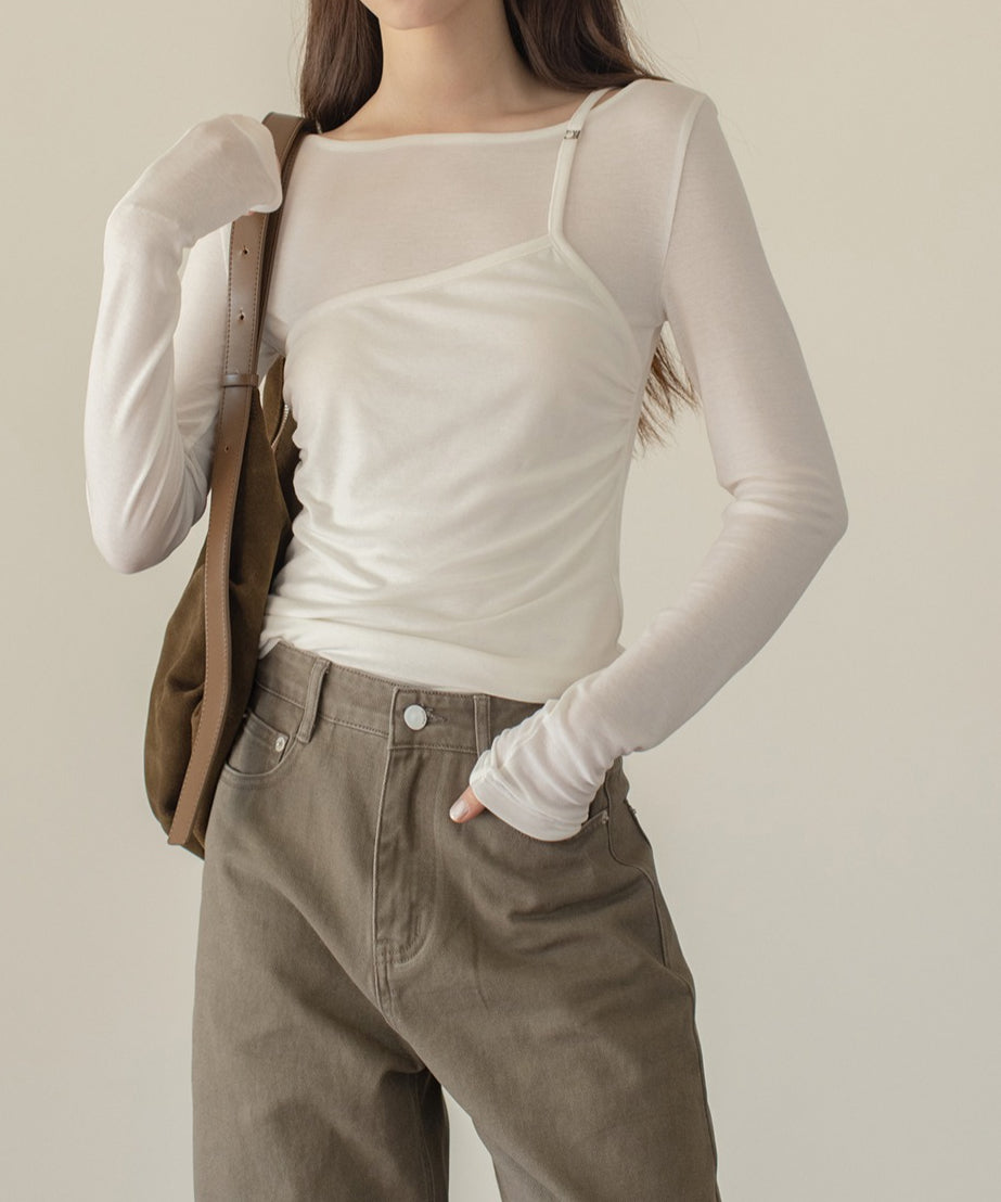 透け感のある薄手のホワイトのロングスリーブトップスを着用した女性の半身。カーキブラウンのワイドパンツとスエード調のバッグを合わせ、パンツのポケットに手を入れたスタイリング。