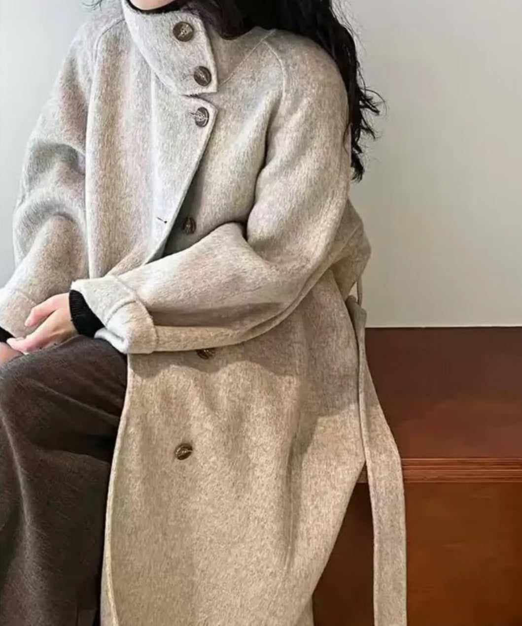 オフホワイトのコートを着用した女性が座っているアップショット。