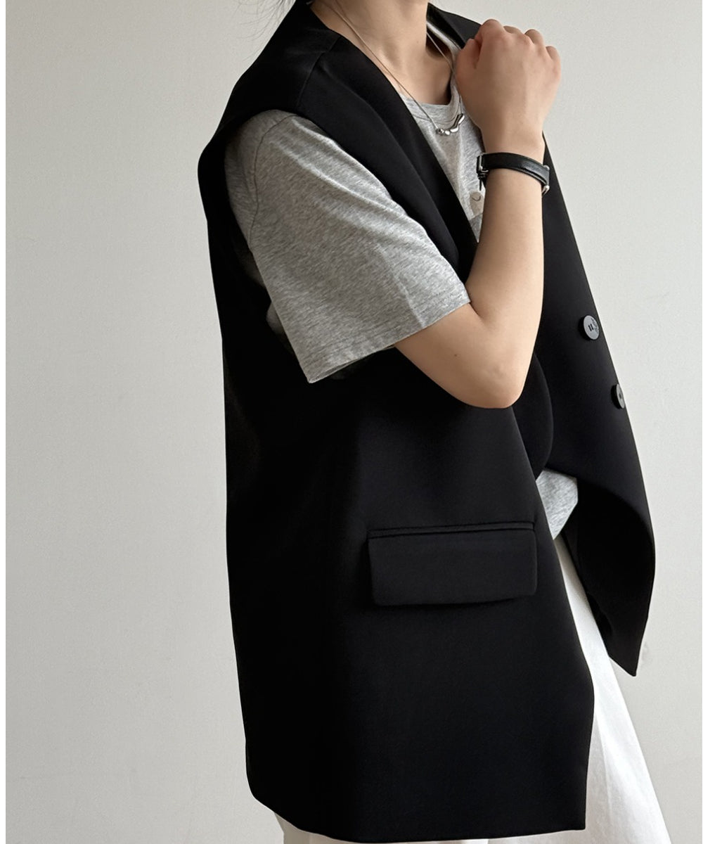 黒のオーバーサイズテーラードジレに、グレーのTシャツと白のボトムスを合わせた女性のコーディネート。