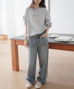 グレーのオーバーサイズスウェットを着用した女性のクローズアップ。胸元には「Summer Night」の赤茶色の刺繍ロゴがある女性の全身。