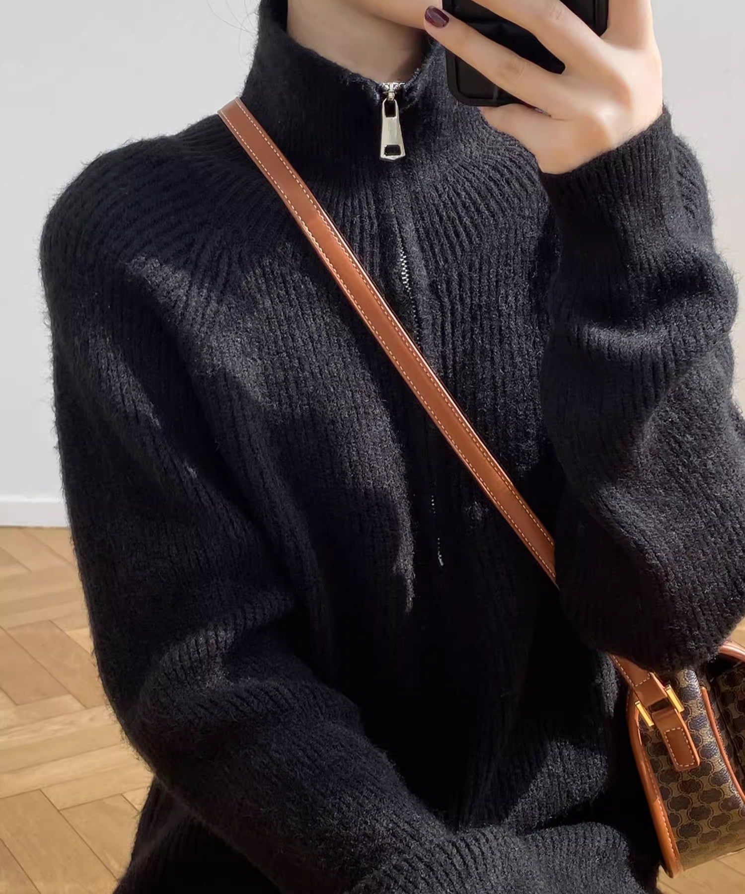 黒のハーフジップニットワンピースを着用し、チェック柄のバッグを斜めがけした女性の上半身のクローズアップ画像。