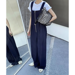 白Tシャツの上にデニムオールインワンを重ね着した女性の全身写真。鏡に映った姿も確認できる。