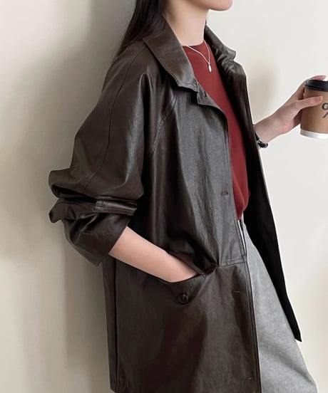 ダークブラウンのジャケットを着た女性がコーヒーカップを持っている画像。