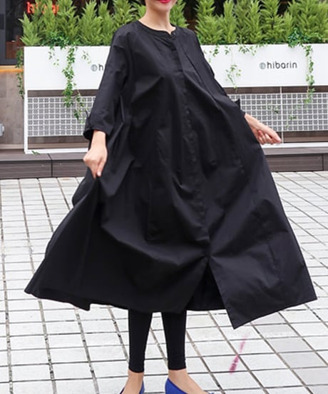 ブラックカラーのロングワンピースを着た女性が道路で軽やかに動いている。