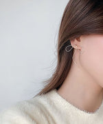 白いニットを着用した女性が、耳にゴールドのリボン型ピアスを付けている様子。