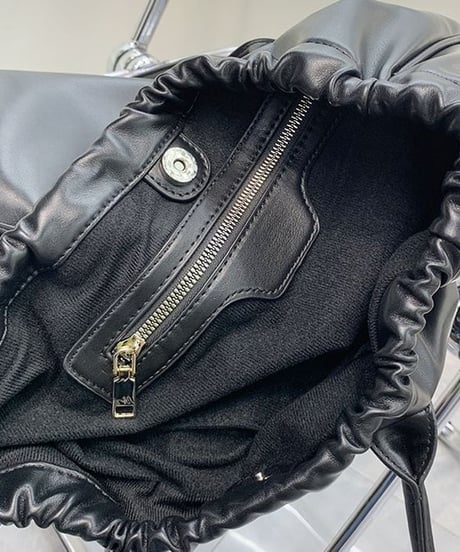 ブラックのフェイクレザートートバッグの開口部のギャザーディテールをクローズアップ。