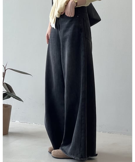 黄色のカーディガンと黒の超ワイドデニムパンツを着用した女性の、足元までのクローズアップ。