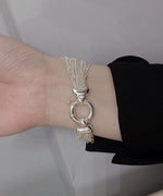 黒い袖の洋服に、繊細な多数のチェーンが束になったデザインのシルバーブレスレットを着用した女性の手首。