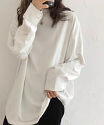白のオーバーサイズ長袖Tシャツ（カットソー）を着用した女性のアップ。袖口はシャツのようなカフスデザインで、ゴールドのネックレスとリングを着用。