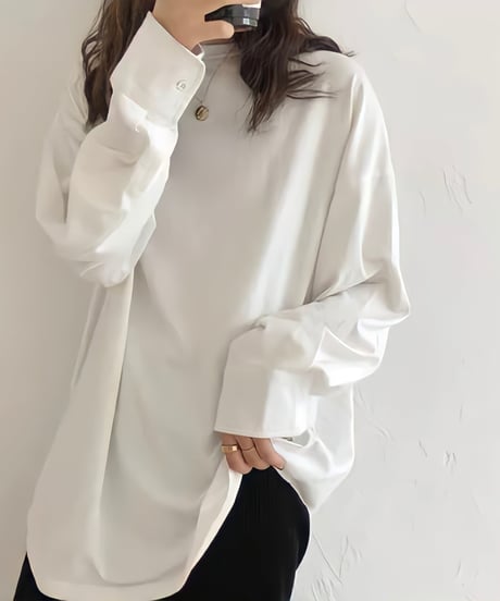 白のオーバーサイズ長袖Tシャツ（カットソー）を着用した女性のアップ。袖口はシャツのようなカフスデザインで、ゴールドのネックレスとリングを着用。