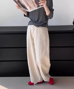 アイボリーのワイドストレートパンツにダークグレーの長袖Tシャツ、赤いスニーカーを合わせた女性の全身コーディネート。
