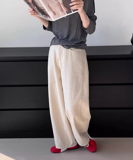 アイボリーのワイドストレートパンツにダークグレーの長袖Tシャツ、赤いスニーカーを合わせた女性の全身コーディネート。