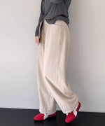アイボリーのワイドストレートパンツにダークグレーの長袖Tシャツ、赤いスニーカーを合わせた女性の全身コーディネート。