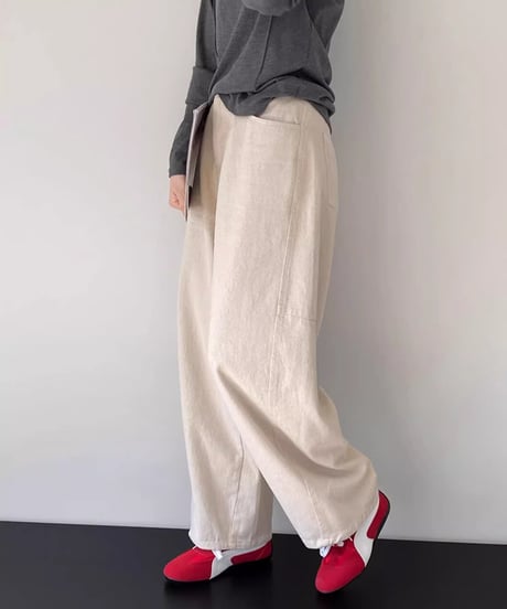 アイボリーのワイドストレートパンツにダークグレーの長袖Tシャツ、赤いスニーカーを合わせた女性の全身コーディネート。