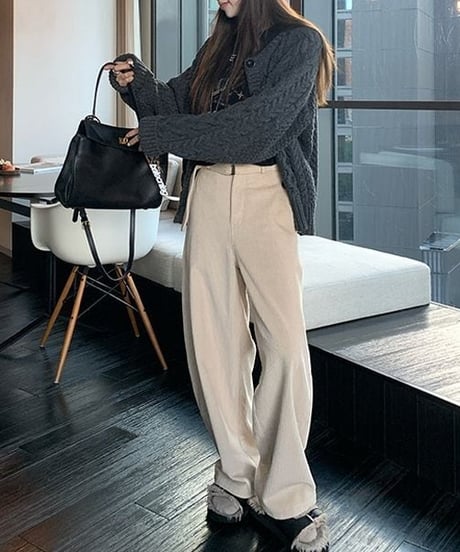 アイボリーの太畝コーデュロイワイドパンツを着用した女性。上部にはグレーのニットを着用し、バッグを持っている