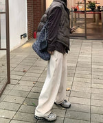 太畝のアイボリーのワイドコーデュロイパンツを着用した女性の全身コーディネート。茶色のダウンベストとシャツを合わせたスタイルを横から見た写真。