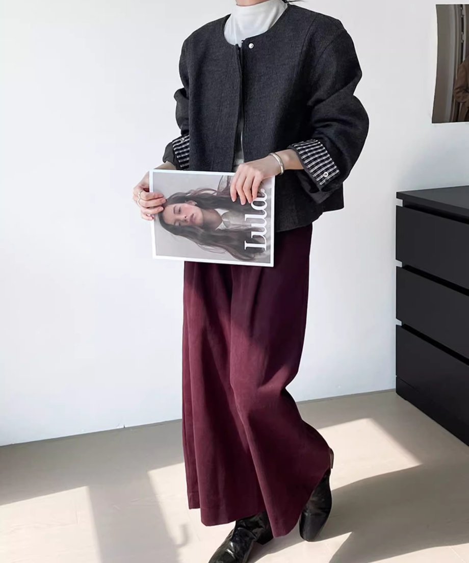 グレーのノーカラージャケットを着用した女性の全身写真。白のハイネックインナーとワインレッドのワイドパンツを合わせたシックな秋コーデ。