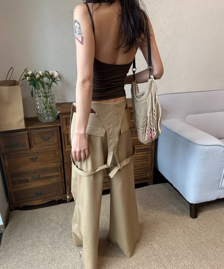 ブラウンタンクトップにカーキのワイドパンツを後ろ姿で着用した女性。肩からバッグを下げている。
