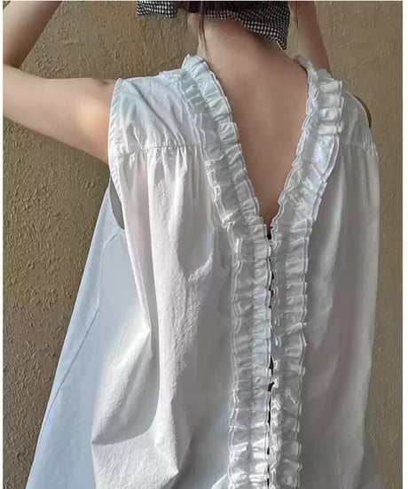 白のフリル付きノースリーブブラウスを着用した女性のバックスタイル。