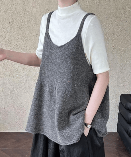黒のハイネックカットソーにアイボリーのウール混チュニックトップスを重ねた女性
