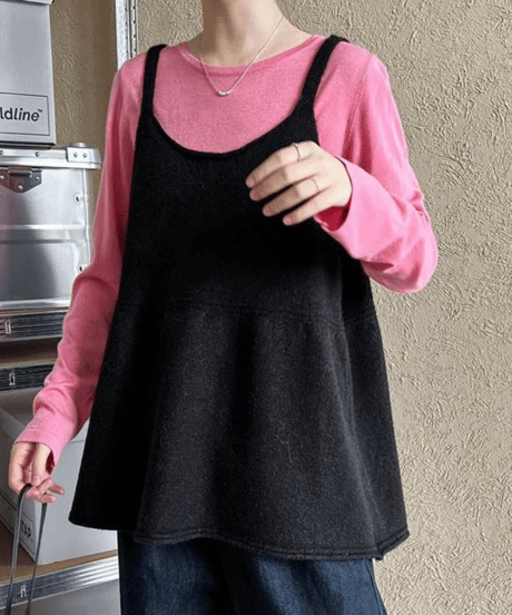 ピンクのインナーにブラックのチュニックトップスを合わせた女性