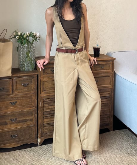 ブラウンタンクトップにカーキのワイドパンツを着用し、室内でポーズを取る女性