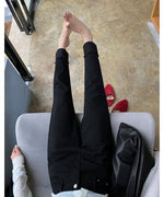 黒の裾カフス付きストレートパンツを着用した女性のパンツ部分のクローズアップ写真。