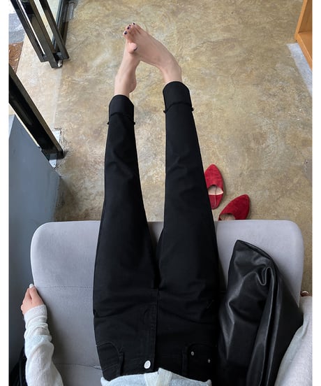 黒の裾カフス付きストレートパンツを着用した女性のパンツ部分のクローズアップ写真。