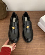 黒のコインモチーフ付きローファーを手に持っている画像。