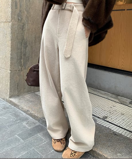 アイボリーの太畝コーデュロイワイドパンツを着用した女性。上部には茶色のファージャケットを着用し、バッグを持っている。