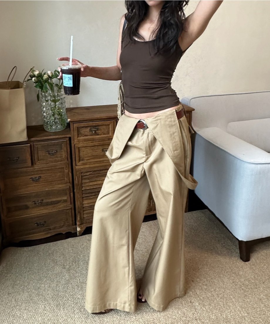 ブラウンタンクトップとカーキのワイドパンツをコーディネートした女性が室内で立っている。