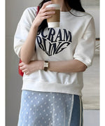 白いTシャツを着た女性が花柄のスカートを合わせて立っている様子。