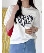 白いTシャツを着た女性が赤いバッグを肩にかけ、カフェでコーヒーを飲んでいる様子。