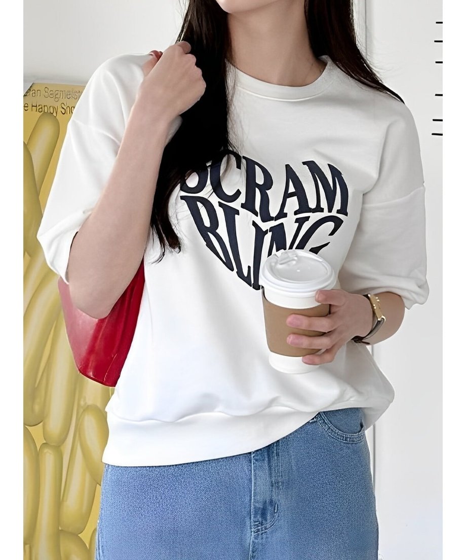 白いTシャツを着た女性が赤いバッグを肩にかけ、カフェでコーヒーを飲んでいる様子。