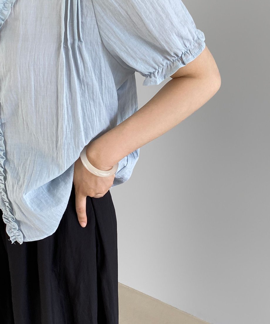 ブルーのブラウスを着た女性がポケットに手を入れている姿。